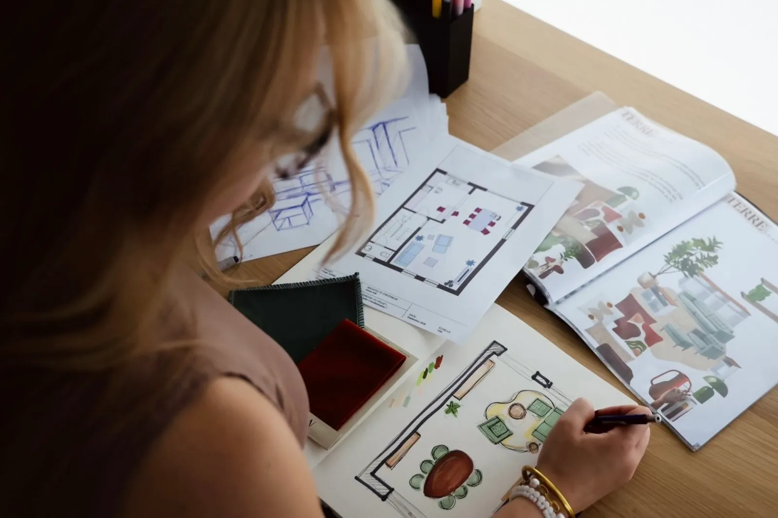 Plan d’aménagement 2D, croquis, échantillons de tissu et planches d’ambiance sur une table de travail